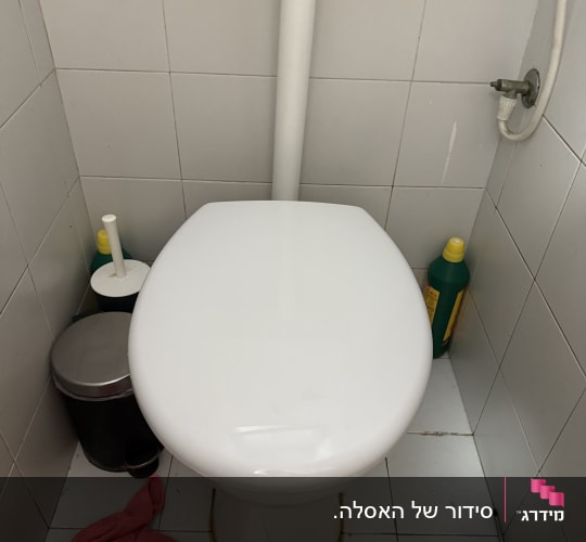 אסלה עם כלי ניקוי וכלי עבודה בחדר שירותים